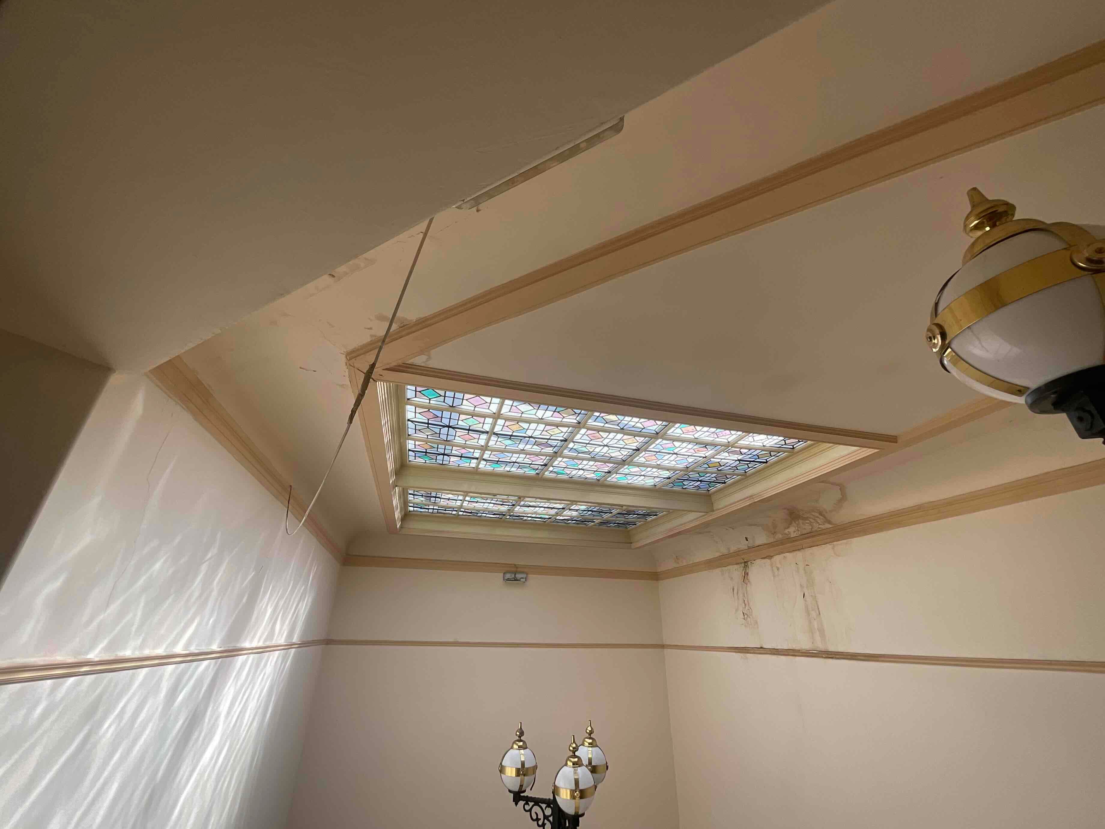 Water damage around a stained glass roof light in a listed commercial building, recorded as dispute evidence.