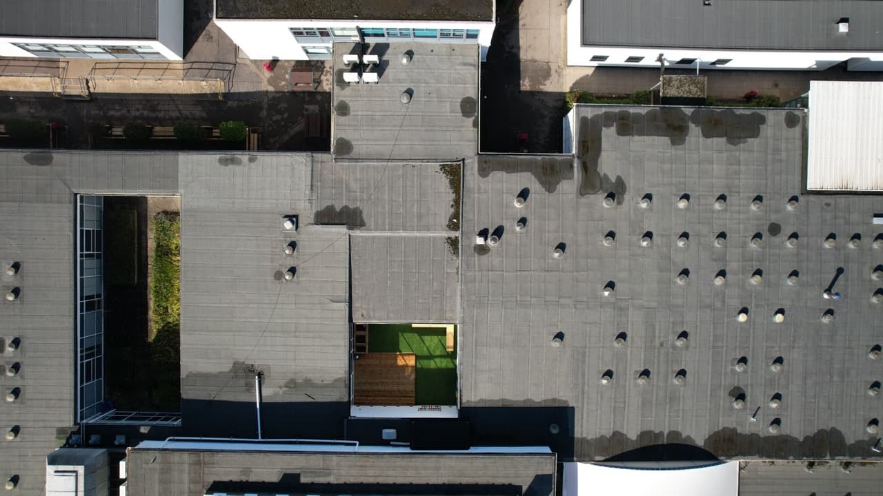 Aerial drone photograph of a commercial roof, representing inspection routes planned to limit site visits.