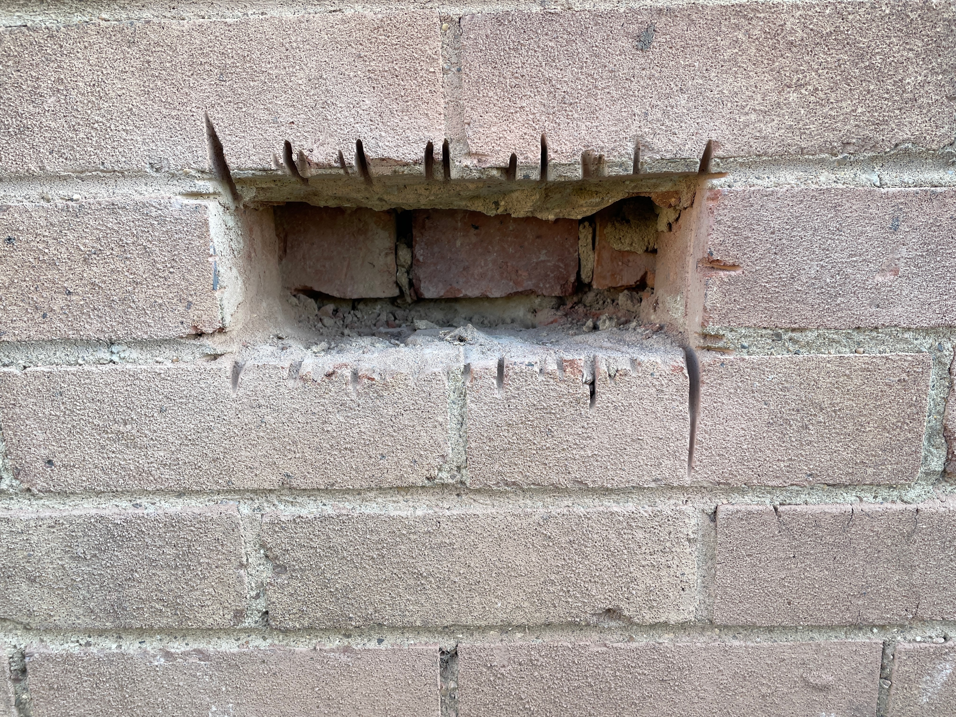 Opening-up inspection of a wall that appeared externally to be cavity construction but required direct examination to confirm the actual wall build-up.